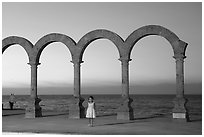 Girl standing by the Malecon arches at sunset, Puerto Vallarta, Jalisco. Jalisco, Mexico (black and white)