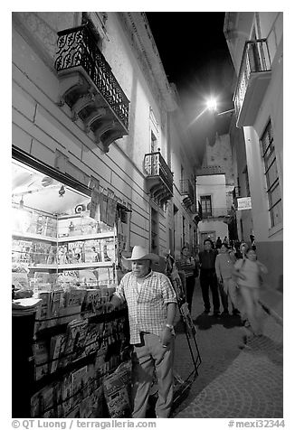 Man at a Newstand booth in a narrow callejone at night. Guanajuato, Mexico (black and white)
