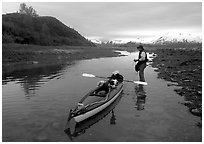 Kayaker tows kayak into a shallow tidal channel into Scidmore Bay. Glacier Bay National Park, Alaska (black and white)