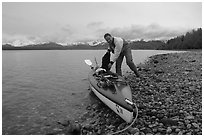 Kayaker loading gear into a double kayak. Glacier Bay National Park, Alaska (black and white)