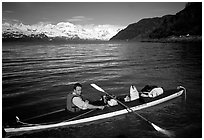 Kayaker sitting at a rear of a double kayak with the Fairweather range in the background. Glacier Bay National Park, Alaska (black and white)