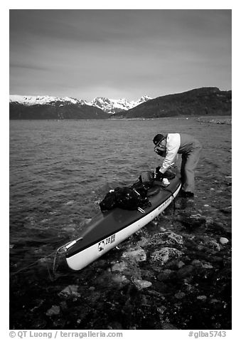 Kayaker tying up gear on top of the kayak,  East Arm. Glacier Bay National Park, Alaska