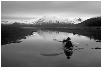 Kayaker paddles in  a shallow tidal channel into Scidmore Bay. Glacier Bay National Park, Alaska (black and white)