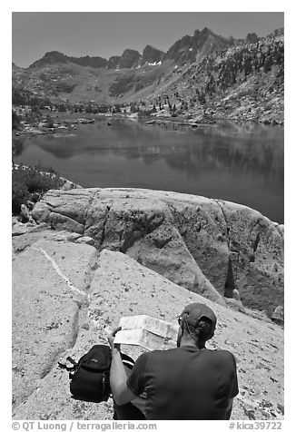 Hiker looking at map in front of lake, lower Dusy Basin. Kings Canyon National Park, California