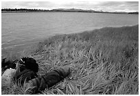 Gear and folded  canoe on a grassy riverbank of the Kobuk River. Kobuk Valley National Park, Alaska (black and white)