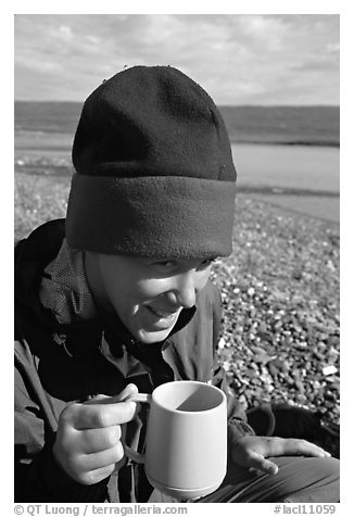 Backpacker drinking from a cup, with mosquitoes on her hat. Lake Clark National Park, Alaska