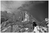 Looking up to woman scrambling on rocks on the East face of Mt Whitney. Sequoia National Park, California (black and white)