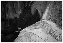 Climber near the top of Lost Arrow spire with Yosemite Falls behind. Yosemite National Park, California (black and white)