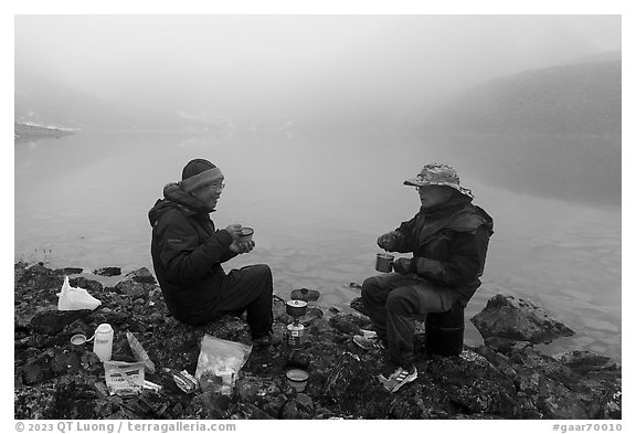 Backpackers eating on shore of foggy lake. Gates of the Arctic National Park (black and white)