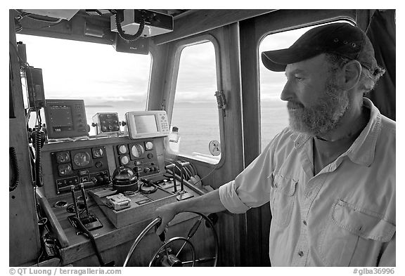 Captain steering boat with navigation instruments. Glacier Bay National Park (black and white)