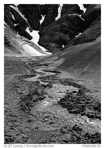Stream flows from the verdant hills into the barren floor of the Valley of Ten Thousand smokes. Katmai National Park (black and white)