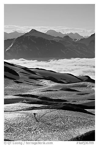 Mountains and sea of clouds, hiker on snow-covered trail. Kenai Fjords National Park (black and white)