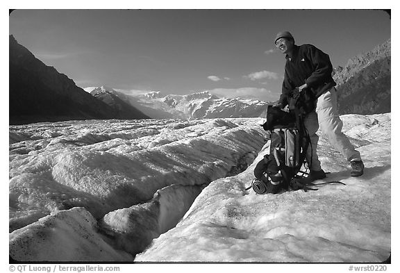 Hiker reaching into backpack on Root glacier. Wrangell-St Elias National Park (black and white)