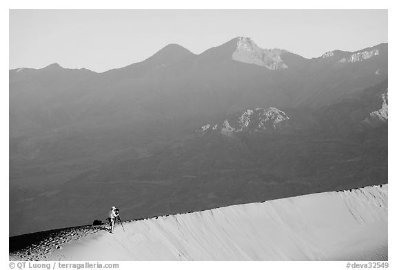 Photographer on dune ridge at sunrise. Death Valley National Park (black and white)