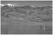 Tourists wading in the rare seasonal lake. Death Valley National Park, California, USA. (black and white)