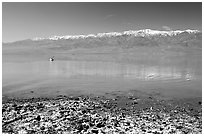 Salt formations, kayaker in a distance, and Panamint range. Death Valley National Park, California, USA. (black and white)