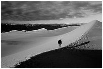 Hiking towards tall dune, the Mesquite Dunes, sunrise. Death Valley National Park, California, USA. (black and white)