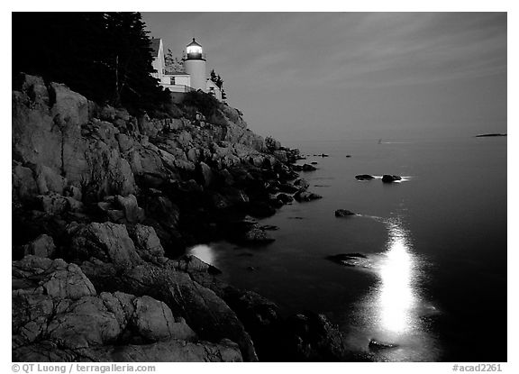 Bass Harbor lighthouse by night with moon reflection in ocean.