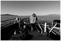 Woman standing on bow of boat sailing towards Annacapa and Santa Cruz Islands. Channel Islands National Park, California, USA. (black and white)