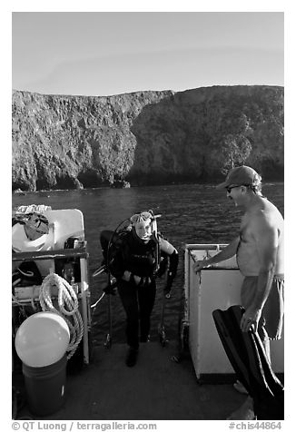 Woman diver stepping onto boat and Annacapa Island. Channel Islands National Park, California, USA.
