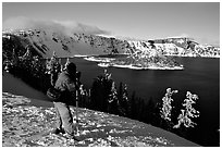 Photographer on  rim of  Lake in winter. Crater Lake National Park, Oregon, USA. (black and white)