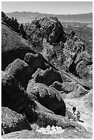 Hikers approaching cliff with steps carved in stone. Pinnacles National Park, California, USA. (black and white)