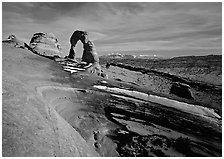 Sandstone bowl, Delicate Arch, and La Sal Mountains with snow, sunset. Arches National Park, Utah, USA. (black and white)