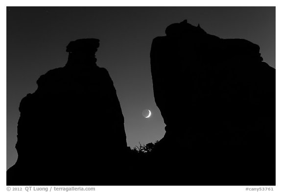 Crescent moon framed by Dollhouse spires. Canyonlands National Park, Utah, USA.