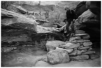 Hiker stepping down on primitive stairs, Maze District. Canyonlands National Park, Utah, USA. (black and white)