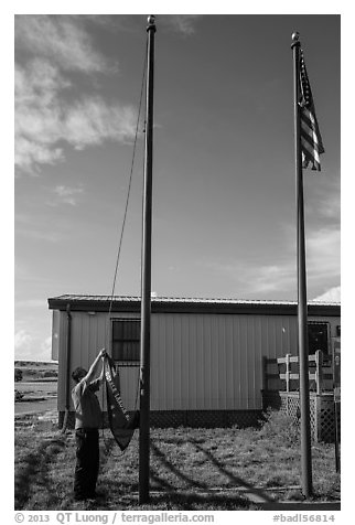 Ranger lowering Ogala Lakota flag, White River Visitor Center. Badlands National Park (black and white)