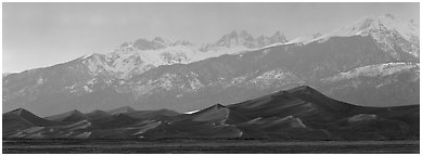 Sand dunes below snowy mountain range at sunset. Great Sand Dunes National Park and Preserve (Panoramic black and white)