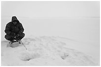 Man ice fishing on frozen Jackson Lake. Grand Teton National Park, Wyoming, USA. (black and white)