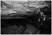 Ranger pointing at speleotherm in large cave room. Wind Cave National Park, South Dakota, USA. (black and white)