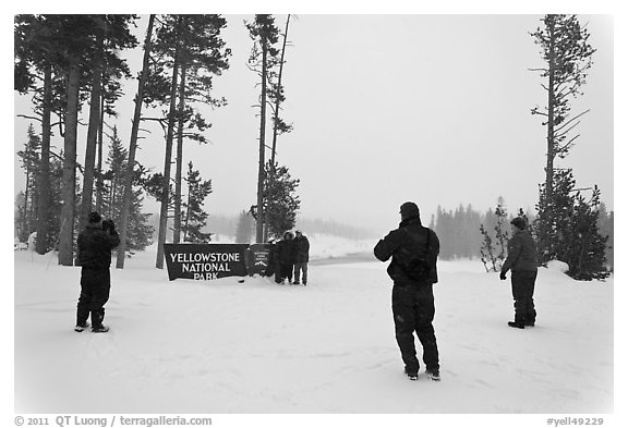 Tourists take pictures with entrance sign in winter. Yellowstone National Park, Wyoming, USA.