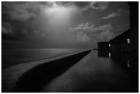 Fort Jefferson seawall at night with sky lit by thunderstorm. Dry Tortugas National Park, Florida, USA. (black and white)