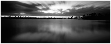 Dark clouds in motion at sunset over lake. Everglades National Park (Panoramic black and white)
