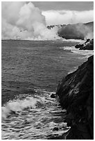 Coast with lava and clouds of smoke and steam produced by lava contact with ocean. Hawaii Volcanoes National Park, Hawaii, USA. (black and white)