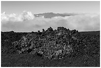 Black of colorful lava on Mauna Loa, Mauna Kea emerging from Saddle clouds. Hawaii Volcanoes National Park, Hawaii, USA. (black and white)
