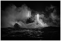 Lava cascades lighting ocean at night. Hawaii Volcanoes National Park, Hawaii, USA. (black and white)
