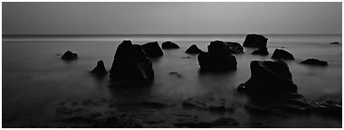Seascape with boulders in water at dusk. National Park of American Samoa (Panoramic black and white)