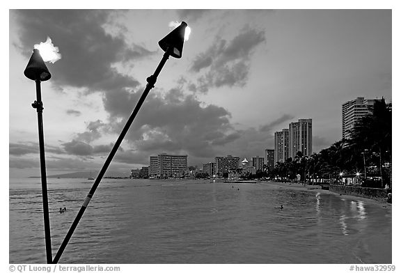 Bare flame torches and skyline at sunset. Waikiki, Honolulu, Oahu island, Hawaii, USA