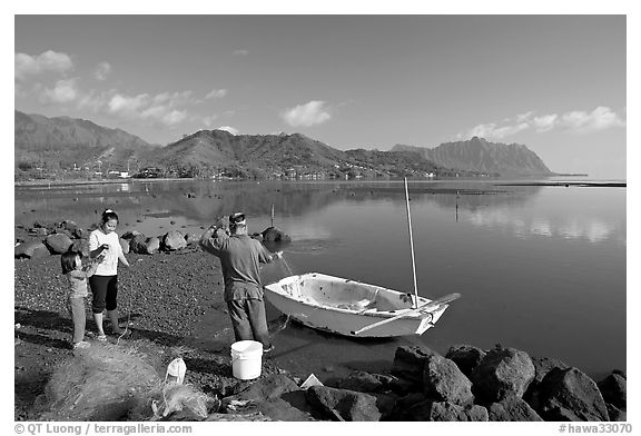 Fisherman and family pulling out net out of small baot, Kaneohe Bay, morning. Oahu island, Hawaii, USA