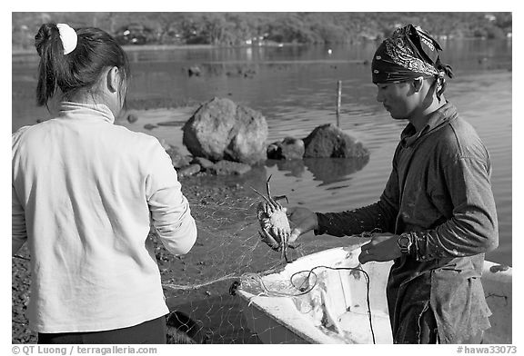Fisherman giving a freshly caught crab to his wife, Kaneohe Bay, morning. Oahu island, Hawaii, USA (black and white)