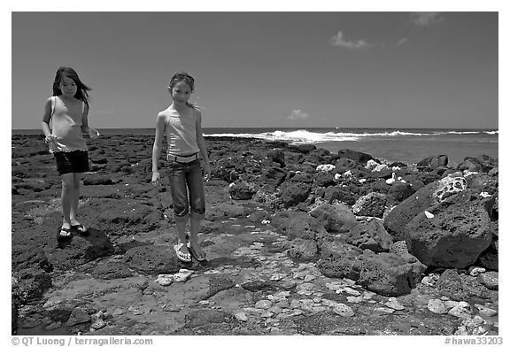Girls playing in tidepool, Kukuila. Kauai island, Hawaii, USA (black and white)