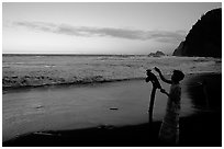 Hawaiian woman piles a stone on a stick as a traditional gesture of reverence, Polulu Beach. Big Island, Hawaii, USA ( black and white)