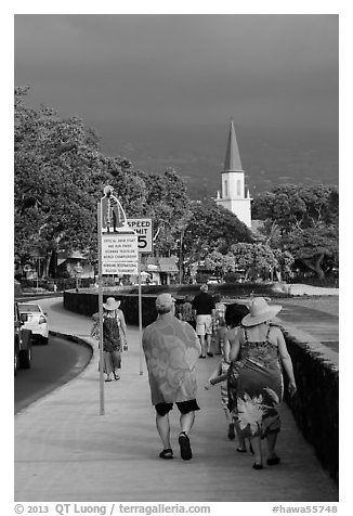 Beachgoers walking past ironman triathlon sign, Kailua-Kona. Hawaii, USA (black and white)
