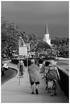 Beachgoers walking past ironman triathlon sign, Kailua-Kona. Hawaii, USA (black and white)