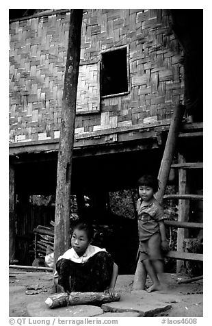 Children near stilt house of a small hamlet. Mekong river, Laos (black and white)