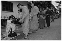 Buddhist monks receiving alm from woman. Luang Prabang, Laos (black and white)
