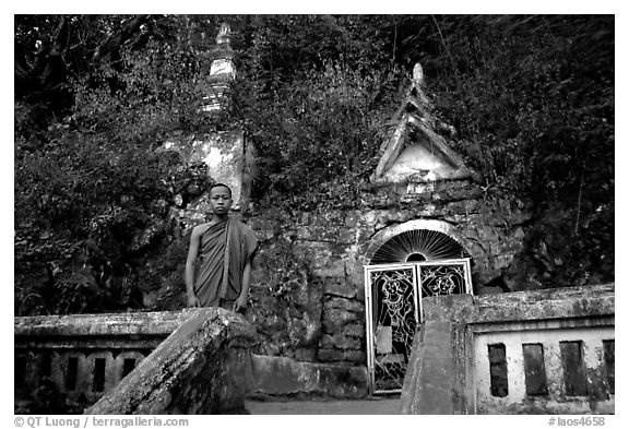 Novice Buddhist monk at entrance of cave, Pak Ou. Laos (black and white)
